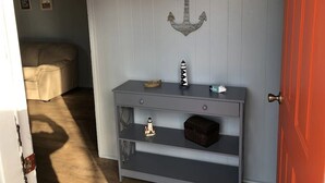 Une pièce avec une console grise adossée à un mur orné d’une décoration représentant une ancre blanche.