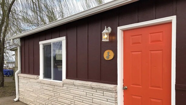 Un bâtiment avec une porte rouge, une fenêtre à cadre blanc et une petite lanterne fixée au mur.