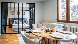 Moderni hotellihuone, jossa on ruokailutila, sänky ja näkymä ulos.