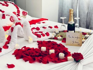 Ambiente romántico con pétalos de rosa, velas, una botella de champán y una nota.