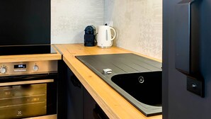 Una cocina compacta con horno integrado, cafetera y lavabo.
