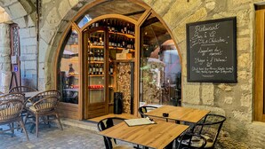 Un café al aire libre con paredes de piedra, mesas y sillas de madera.