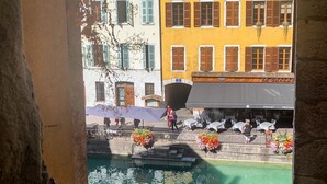 Vista de un canal con un bote, una zona de estar al aire libre y edificios con contraventanas.
