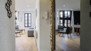 Un interior moderno con suelo de madera, sofás grises y un espejo grande.