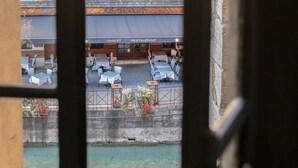 Un área de estar al aire libre con mesas y sillas, un edificio con un letrero que dice "LE CHALET RESTAURANT", y vista de un canal.