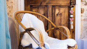 Una silla de mimbre con un cojín blanco y mullido frente a una puerta de madera.