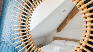 A room with a circular wooden frame mirror, a bed with white linens, and a blue textured wall. - Duplex d'Albigny 3 minutes du lac (Annecy)