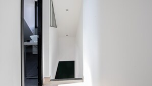 A modern interior with a staircase leading to a dark room, a white wall, and a small window. - Duplex d'Albigny 3 minutes du lac (Annecy)