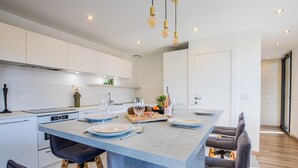 A modern kitchen with a central island, white cabinetry, and pendant lighting. - Duplex d'Albigny 3 minutes du lac (Annecy)