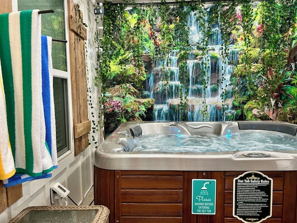 Un jacuzzi con un fondo de cascada, un perchero y un cartel de seguridad.