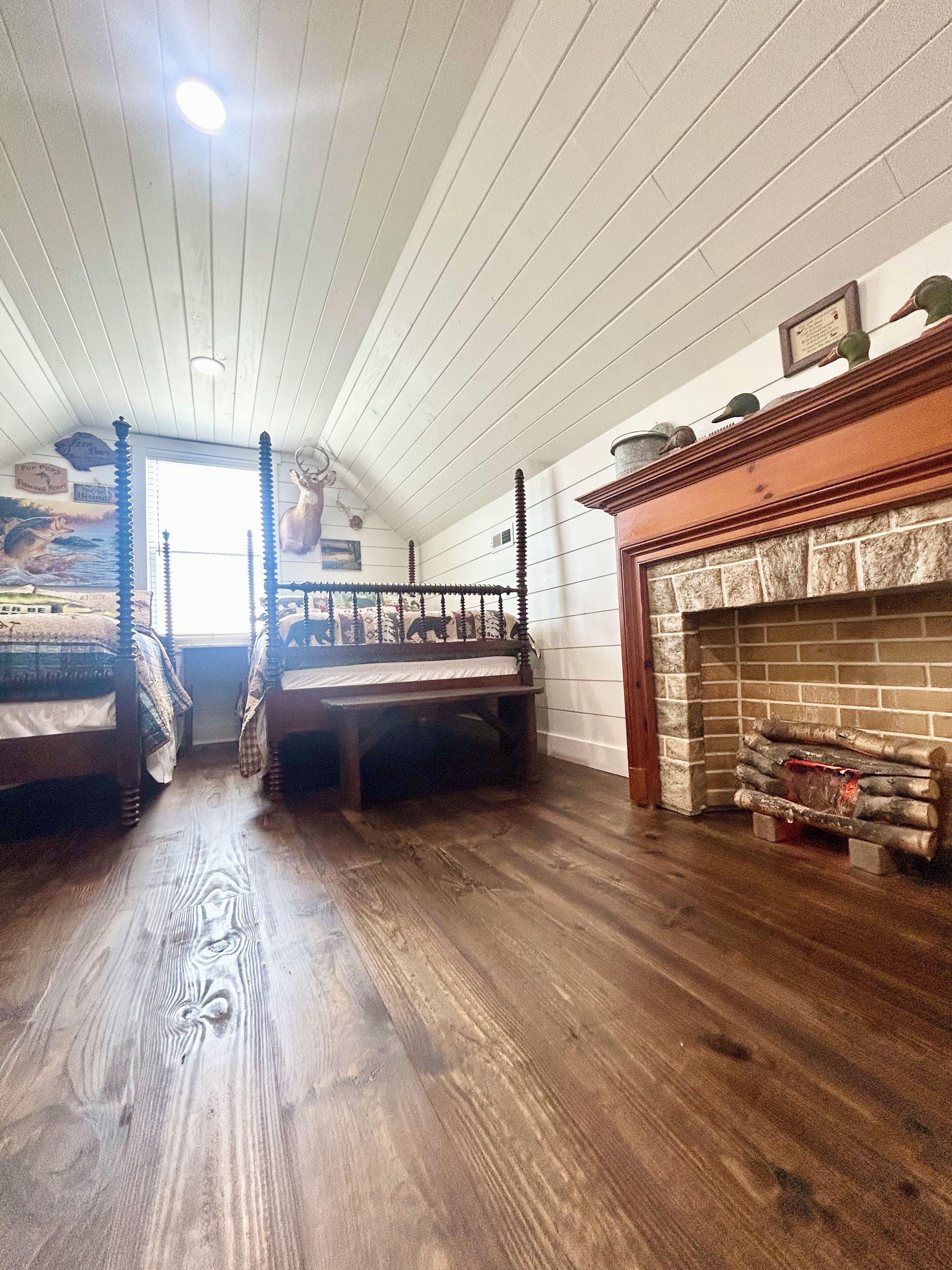 A room with two beds, a fireplace, and a ceiling fan.