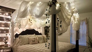 A four-poster canopy bed with white bedding and decorative pillows, a wooden headboard, and a bedside table with a candle holder. - NEW CABIN ~HOT TUB IN THEATER~1 QUIET ACRE ~HIKING ~FIRE PIT ~KING SUITES (Columbia)