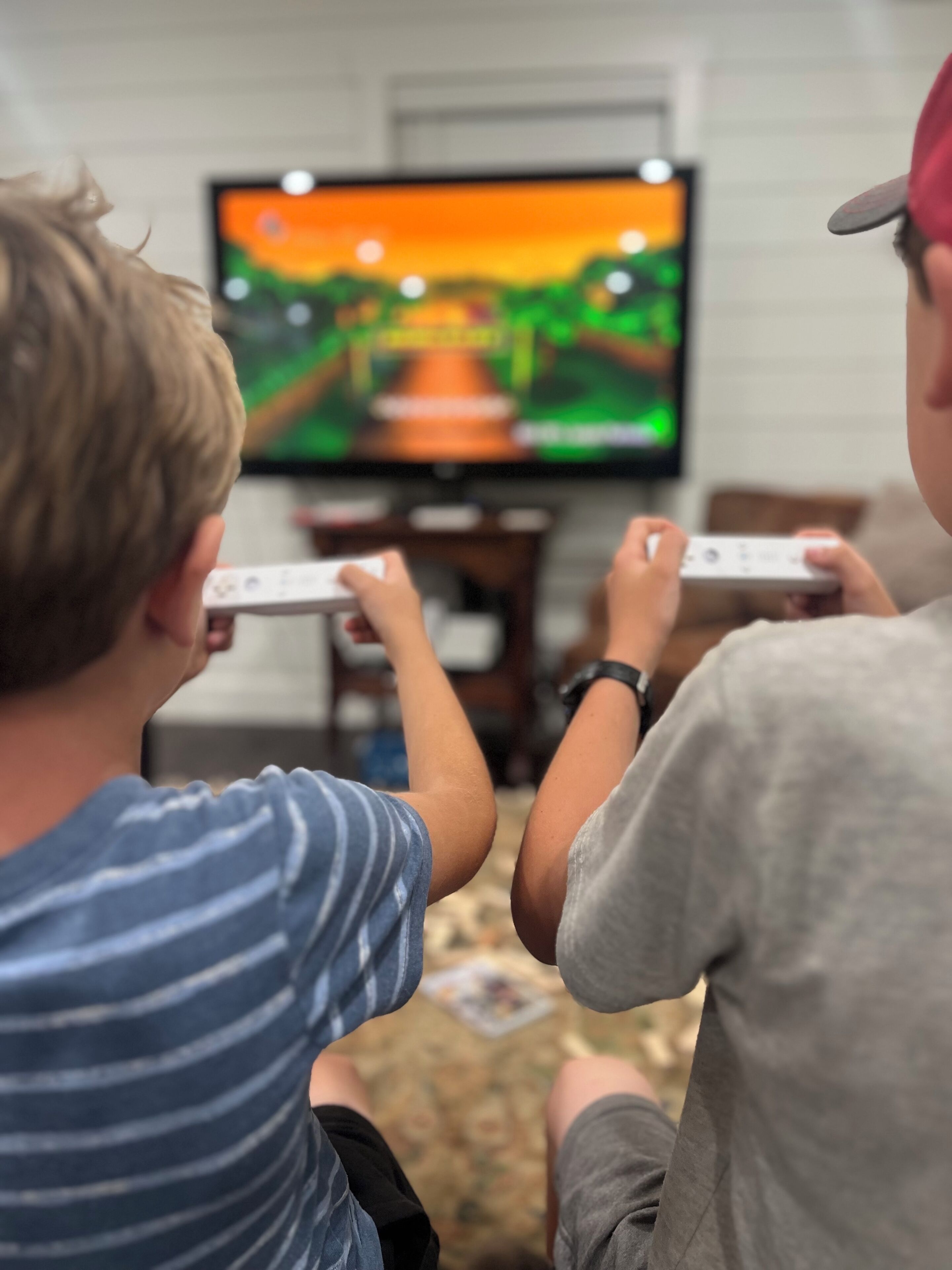 Two individuals playing video games with controllers in a room with a television displaying a game.