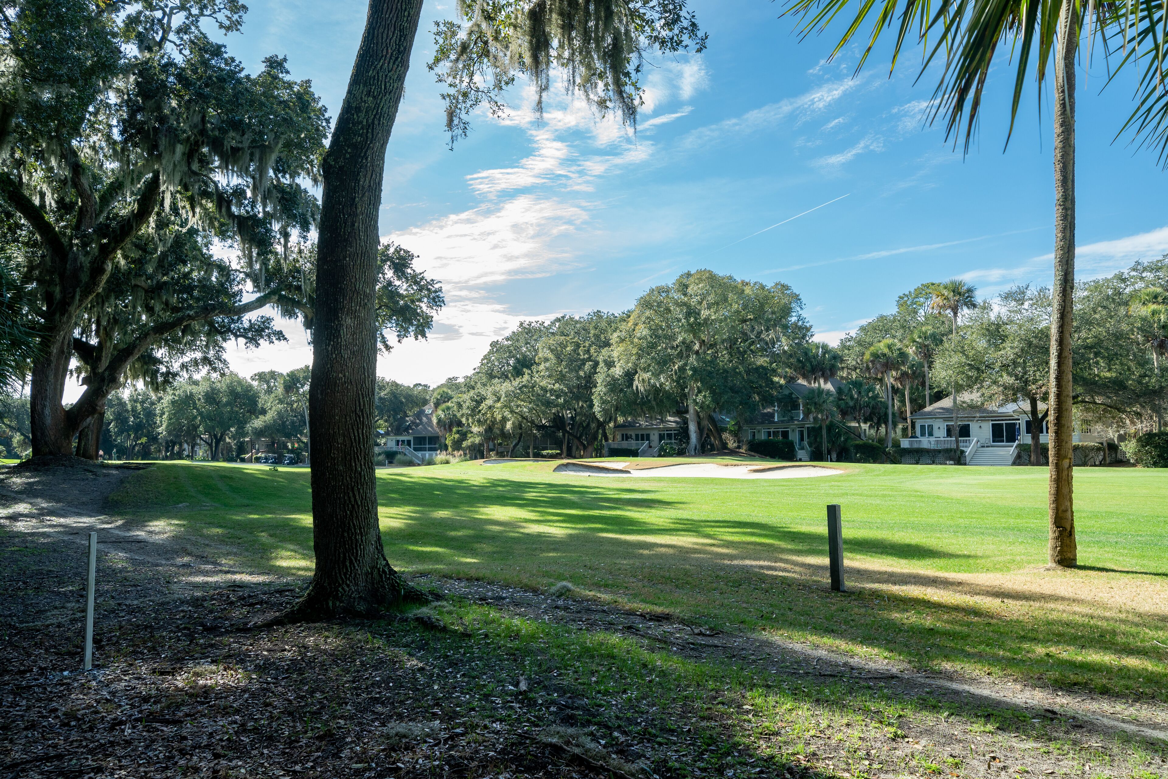 A golf course with a clear path, trees, and a distant building.