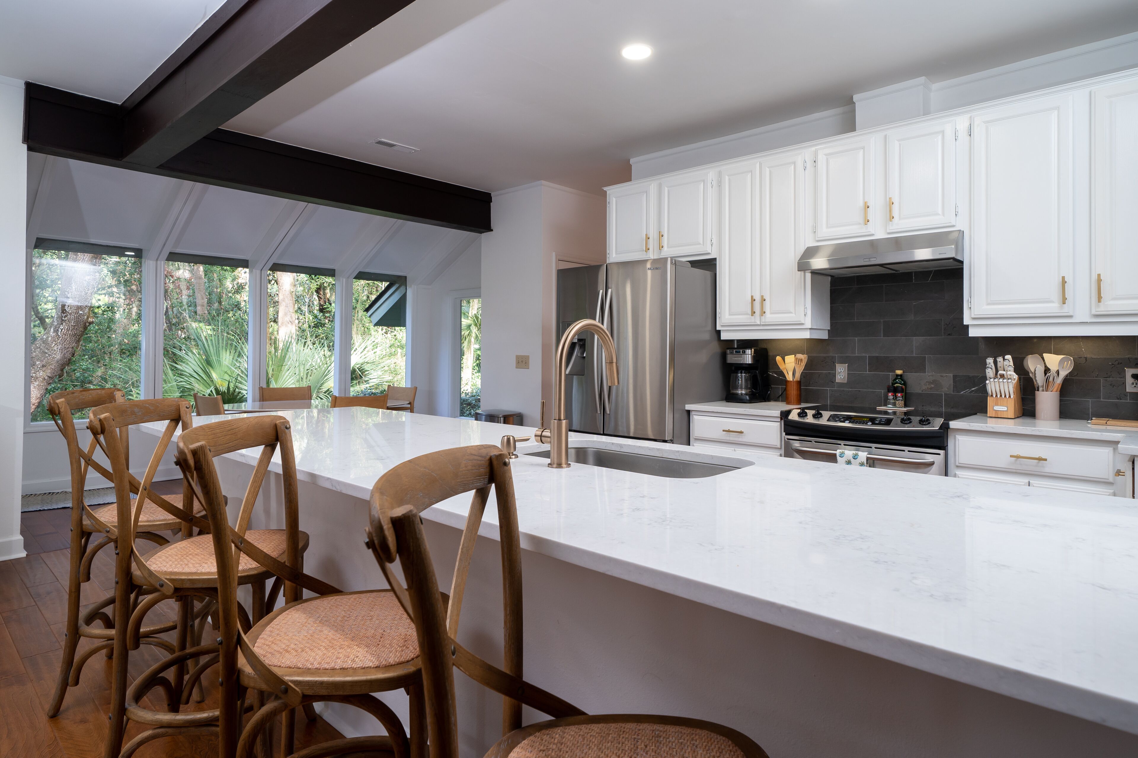 A modern kitchen with white cabinetry, stainless steel appliances, and a large island with bar stools.
