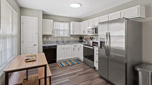 A compact kitchen with white cabinets, a stainless steel refrigerator, a microwave, and a dishwasher. - Sleeps 8. Cozy Bungalow in Downtown Georgetown (Georgetown)