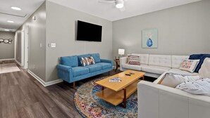 A modern living room with a blue sofa, a white sofa, a wooden coffee table, and a ceiling fan. - Sleeps 8. Cozy Bungalow in Downtown Georgetown (Georgetown)