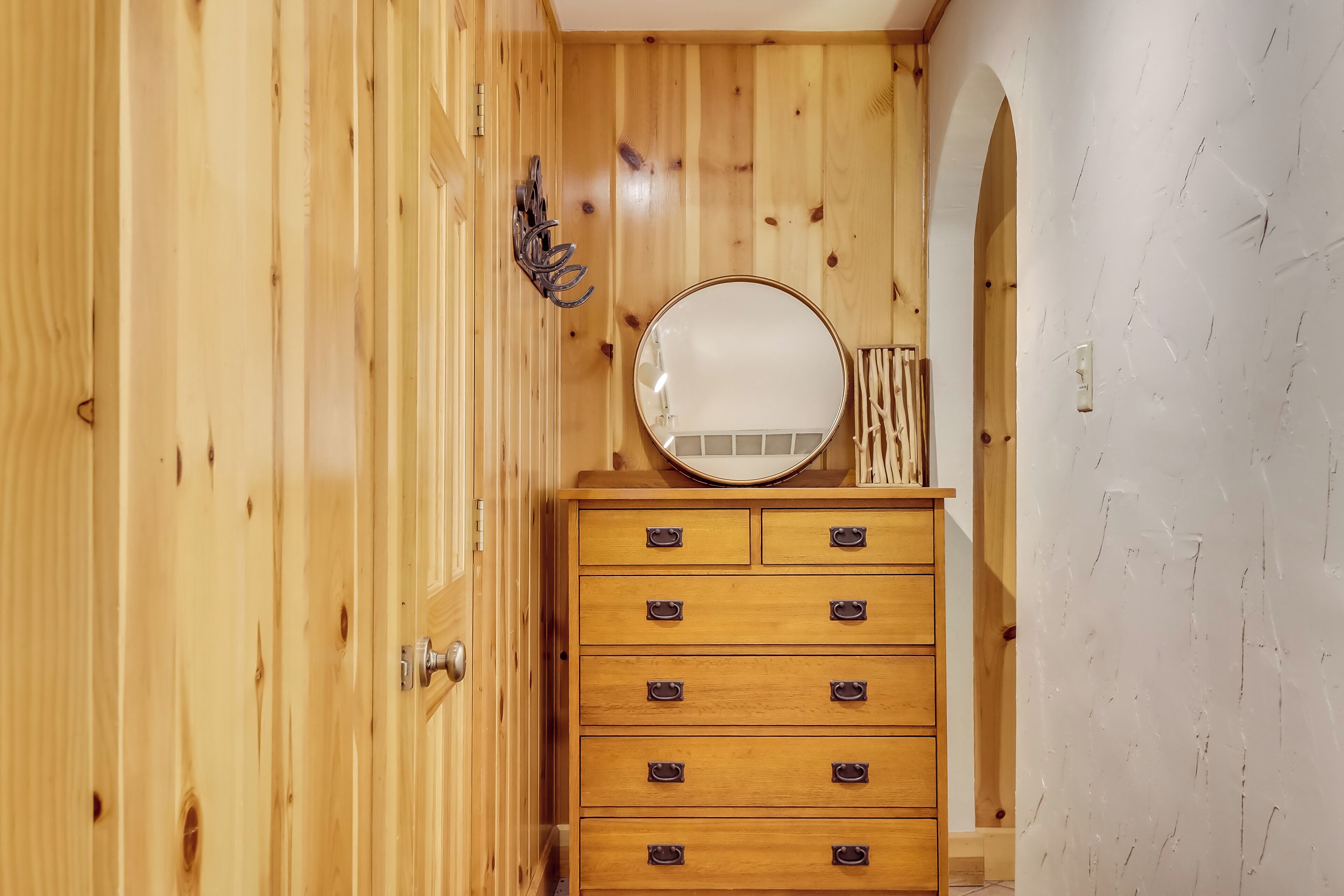 Une armoire en bois avec plusieurs tiroirs et un miroir rond placé au-dessus.