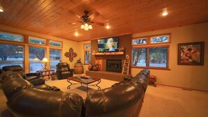 A cozy living room with a fireplace, leather sofas, a television, and large windows. - Let's Birdie!! (Alto)