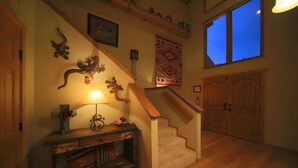 A staircase with a wooden handrail, a wall-mounted lamp, and a decorative wall hanging. - Let's Birdie!! (Alto)