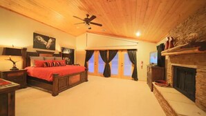 A bedroom with a wooden ceiling, a bed with red bedding, a fireplace, and a large window with curtains. - Let's Birdie!! (Alto)