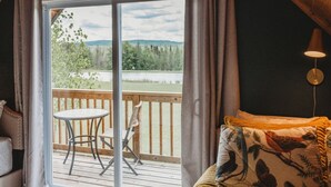 Una habitación acogedora con cama, una mesa y vistas a una terraza y al paisaje.