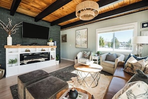 A modern living room with a fireplace, comfortable seating, and a large window offering a view of the outdoors.