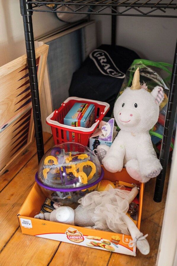 Un pequeño depósito de almacenamiento con un unicornio de juguete, una cesta roja y un recipiente de plástico lleno de juguetes.