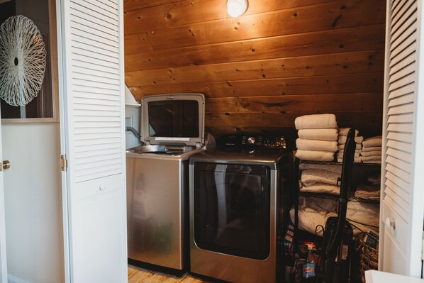 A compact laundry room with a washing machine, dryer, and stacked towels.