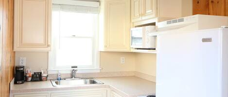 A kitchen with white cabinets, a sink, a stove, and a microwave.