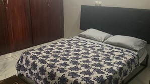 Een slaapkamer met een bed, een houten garderobe en een nachtkastje.