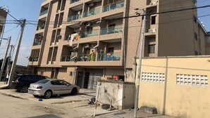 Een meerlaags gebouw met balkons, airconditioning en een hekwerk.