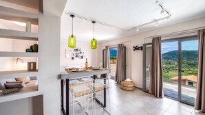 A modern kitchen with a dining area, large windows with a view, and a balcony. - Villa Irene 1 Drakatos (Lefkada)