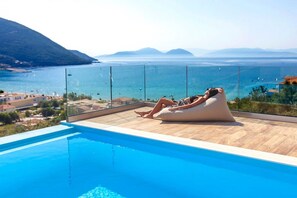 A person relaxing on a bean bag chair by a pool with a view of the sea and mountains. - Villa Irene 1 Drakatos (Lefkada)