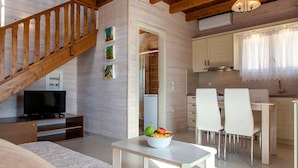 Un salon moderne avec un escalier en bois, un coin repas avec des chaises blanches et une cuisine avec des meubles blancs.