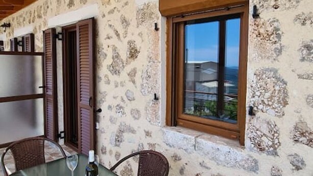 Ein Essbereich mit Tisch und Stühlen, einer Weinflasche und Blick durch ein Fenster.
