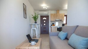 Ein modernes Wohnzimmer mit einem grauen Sofa, einem Holztisch mit einem Laptop und einer Topfpflanze.