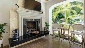 A fireplace with a stone facade, a black countertop, and a seating area with wicker chairs and a table.
