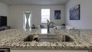 Een moderne keuken met een granieten aanrecht, een roestvrijstalen spoelbak en een geïntegreerde vaatwasser.