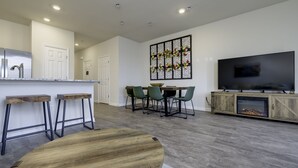 Een moderne woonkamer met een eethoek, een keuken met een roestvrijstalen koelkast, een flatscreen televisie en een open haard.