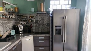 Una cocina con un refrigerador de acero inoxidable, una tostadora y varios utensilios de cocina sobre la encimera.