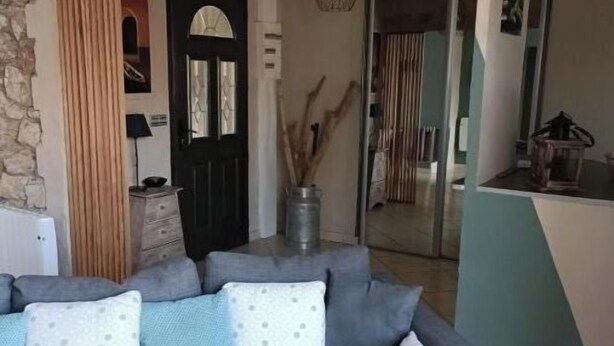 Una sala de estar con un sofá gris, una pared de piedra y una puerta de madera.