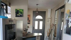 Cocina compacta con refrigerador, horno y un taburete pequeño.