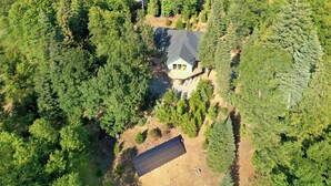 Une maison entourée d’une forêt dense, avec une montagne en arrière-plan.