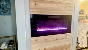 Une cheminée murale avec un panneau décoratif en bois, une étagère pour les serviettes et un porte-peignoir.