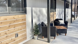 Un espace extérieur aménagé, abrité et doté de mobilier en osier et d’une petite plante en pot.