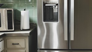 A stainless steel refrigerator with a built-in ice maker, a microwave, and a small oven.