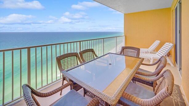 A balcony with wicker furniture, a glass table, and a view of the ocean. - Beachfront condo w/ pool, hot tub & gym (Panama City Beach)