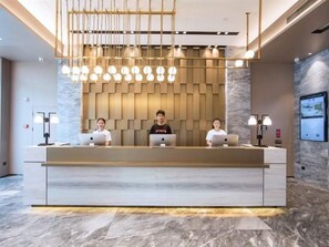 A reception desk with three staff members, a modern chandelier, and a marble floor. - Atour Hotel (Ma'anshan)