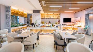 Un restaurante moderno con suelo de mármol, paneles de techo de madera y una zona de bar central.